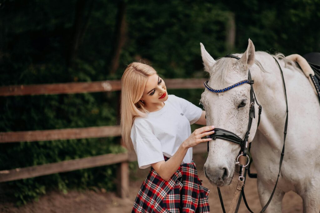 pexels photo 29092665 29092665 A young woman affectionately interacts with a white horse in a rustic outdoor setting.